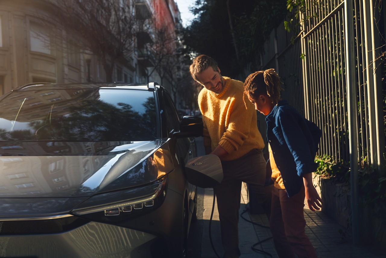 A family charges their Toyota bZ4X at a public charging station